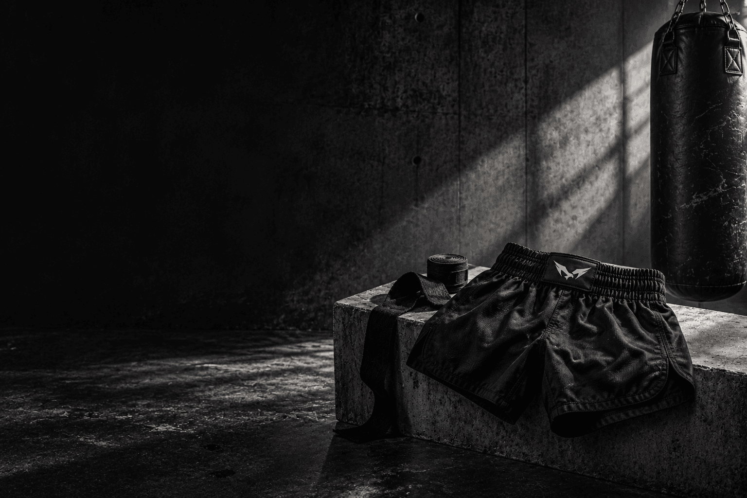 Dark training-studio campaign still life with wrapped hands and fightwear